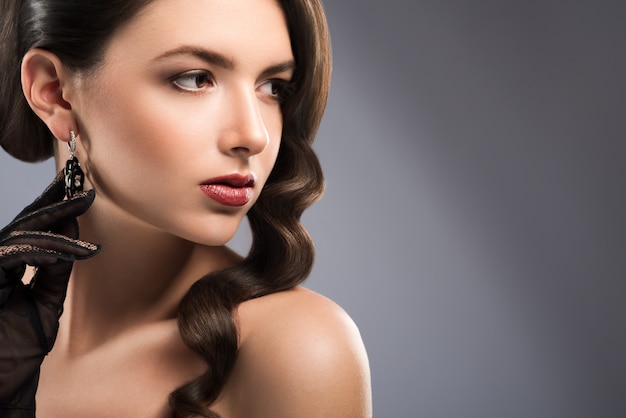 Close up portrait of a gorgeous brunette woman with red lips posing gracefully looking away