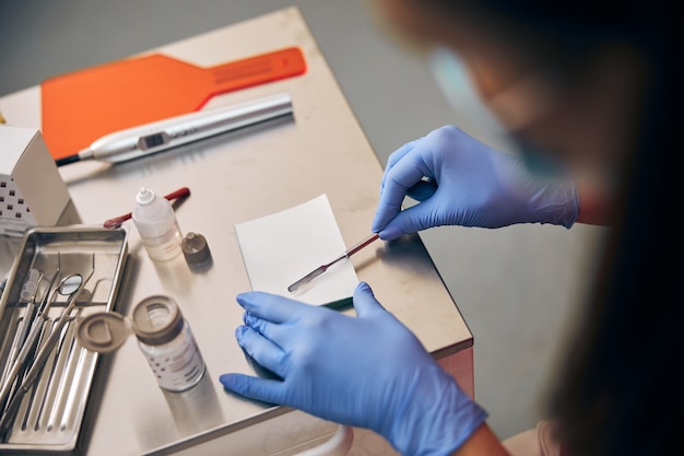 Close up portrait of hands of the assistant to the stomatologist with a preparation for preparation of a filling mixture