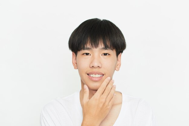 白い壁にハンサムなかわいい若いアジア人男性の肖像画をクローズアップ