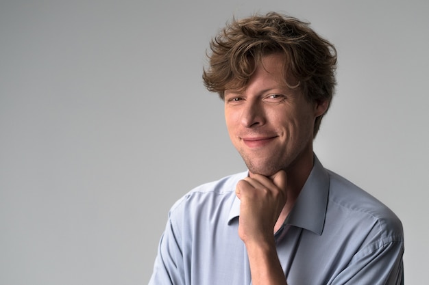 Close up portrait of a handsome man in blue shirt leaned chin on a fist