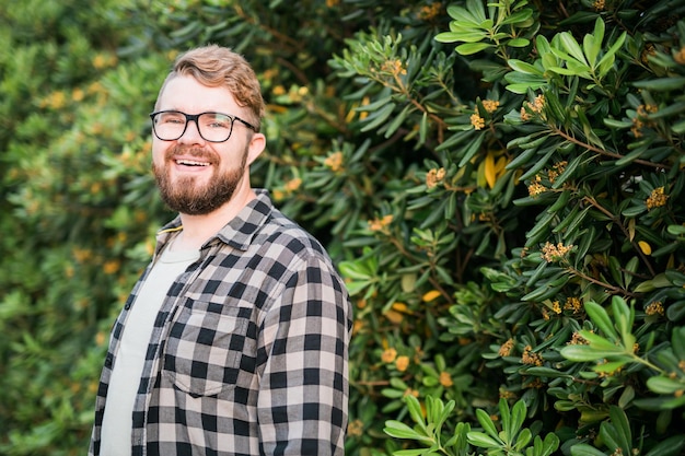 Close up portrait handsome young man over green bush outside copy space and place for advertising