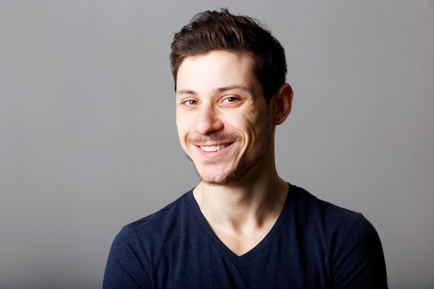 Close up portrait of handsome young man smiling against gray background