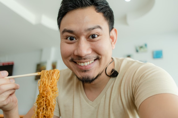 幸せなアジア人の肖像画を閉じる麺を食べる。