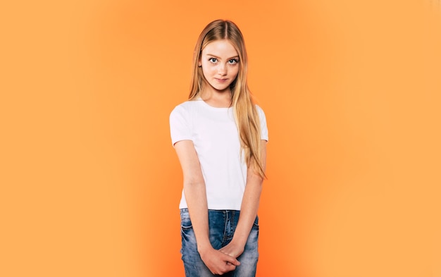 Close up portrait of happy attractive and cute blonde little girl with long hair while she is posing isolated in studio and smiling