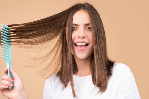 Close up portrait of happy beautiful girl with shiny hair with comb