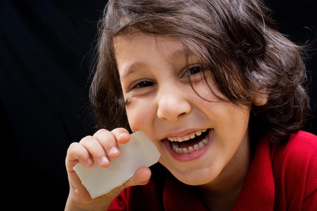 Photo close-up portrait of happy boy with paper against black background