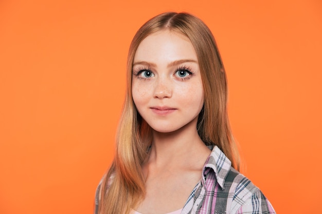 Close up portrait of happy cute blonde little girl with long hair while she is posing isolated in studio and smiling