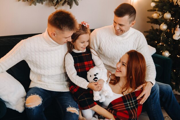 Close-up portrait of a happy family sitting on a sofa near a Christmas tree celebrating a holiday