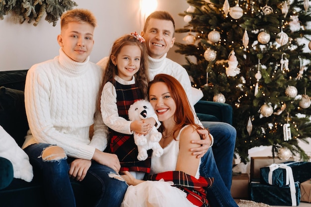 Close-up portrait of a happy family sitting on a sofa near a Christmas tree celebrating a holiday