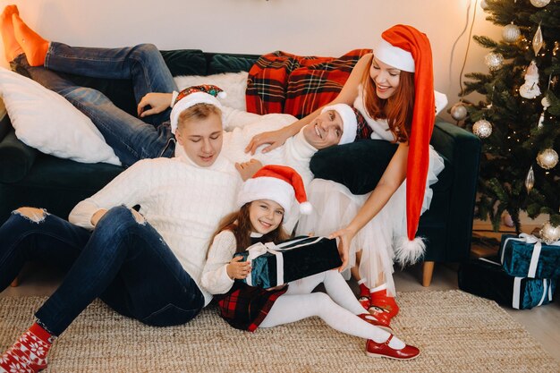 Макро портрет счастливой семьи, сидящей на диване возле елки, празднует праздник