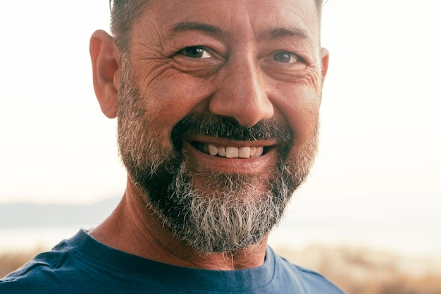 Close up portrait of happy man cheerful looking on camera One adult mature male caucasian smile with confident and serene expression White outdoor sky background People and age happiness lifestyle