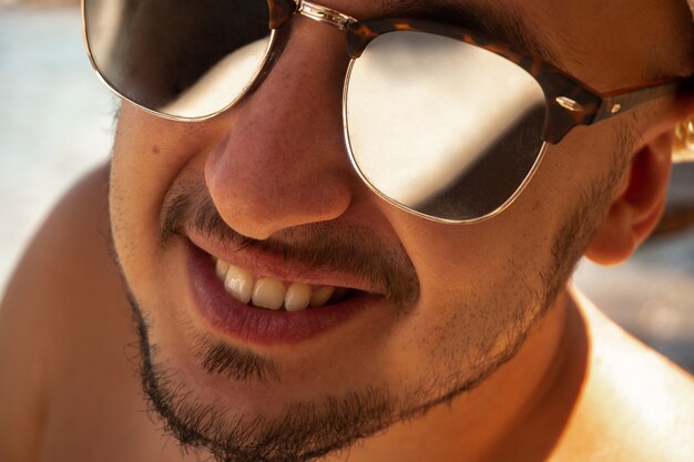 Крупным планом портрет счастливого человека в солнцезащитных очках, смотрящего в камеру