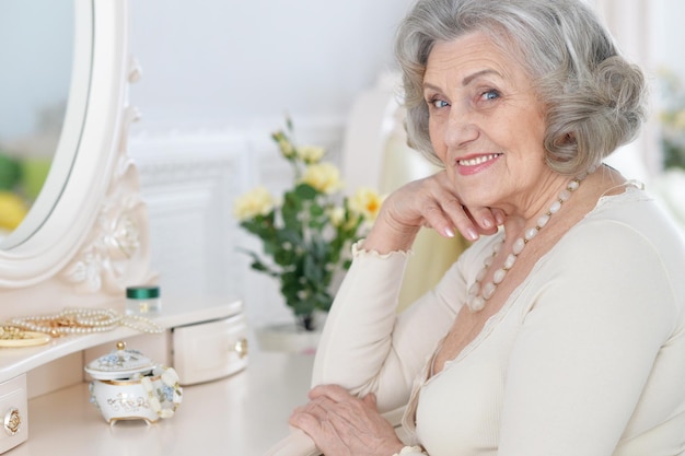 Close up portrait of happy senior woman sitting near dressing table