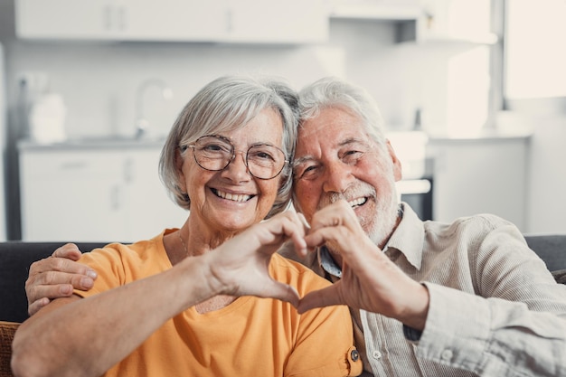 Photo close up portrait happy sincere middle aged elderly retired family couple making heart gesture