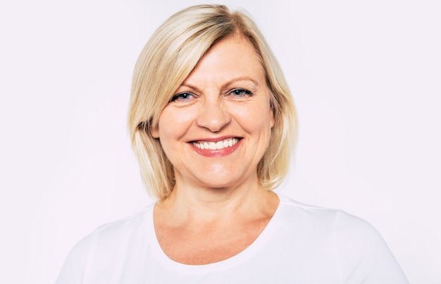 Close up portrait of happy smiling and beautiful blonde senior woman isolated on white background and posing with smile on camera