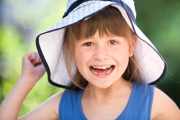 Ritratto del primo piano della bambina sorridente felice in un grande cappello. bambino che si diverte tempo all'aperto in estate.