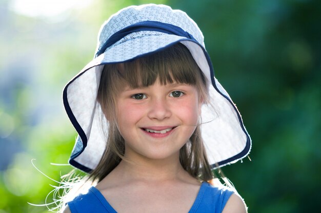 Close-up portrait of happy smiling little girl in a big hat.