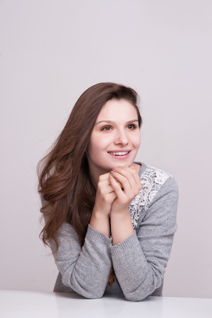 Close up portrait of a happy smiling woman resting her chin on her hands and looking directly at the camera