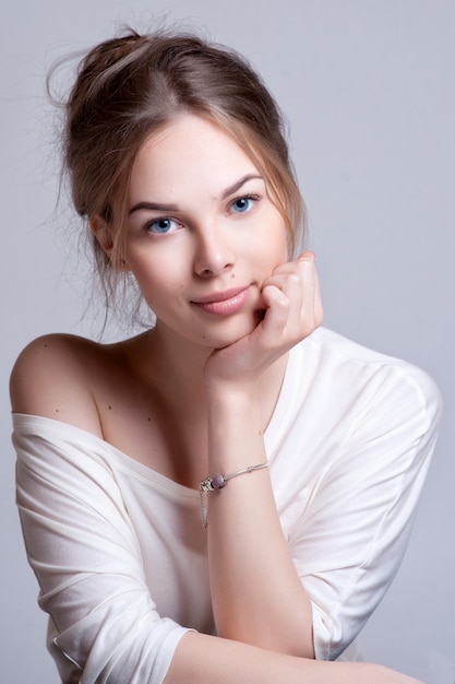 Close up portrait of a happy smiling woman resting her chin on her hands and looking directly at the camera