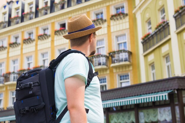 バックパックを持って旅行している幸せな若い男の肖像画を閉じます。