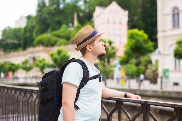 バックパックを持って旅行している幸せな若い男の肖像画を閉じます。