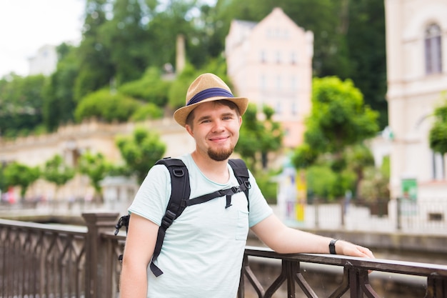 バックパックを持って旅行している幸せな若い男の肖像画を閉じます。