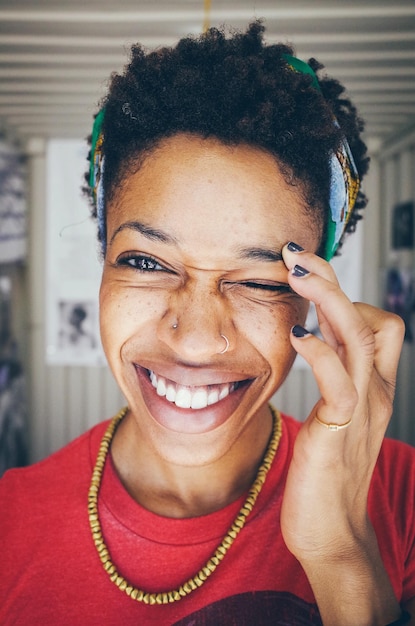 Close-up portrait of happy young woman winking at home