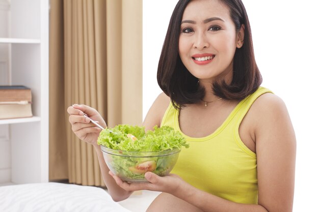 Close up portrait of healthy pregnant woman eating fresh salad for breakfast