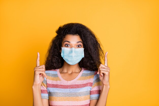 Close-up portrait of her she attractive wavy-haired girl pointing up wearing gauze mask stop flu grippe mers cov idea solution medicine isolated on bright vivid shine vibrant yellow color background