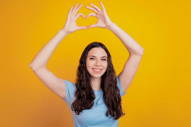 彼女のクローズアップの肖像画彼女は素敵な魅力的な夢のようなかわいいかわいい心のシンボルサイン孤立した明るい鮮やかな色の背景を示しています