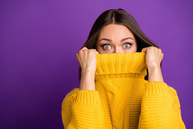 Ritratto del primo piano di lei bella attraente bella divertente spaventata ragazza dai capelli lisci che nasconde il viso in maglione caldo.