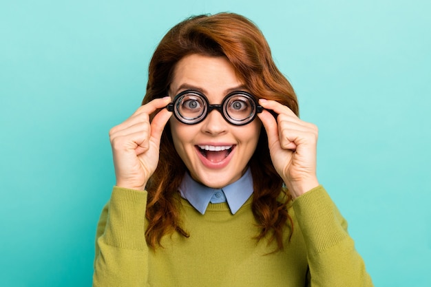 Close-up portrait of her she nice attractive overjoyed ecstatic creative cheerful cheery wavy-haired girl touching thick glasses isolated on bright vivid shine vibrant teal turquoise color background