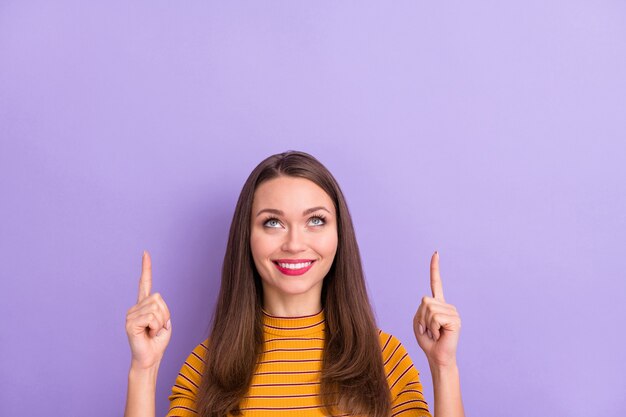 Close-up portrait of her she nice attractive pretty cute cheerful cheery glad girl pointing two forefingers up ad copy space isolated over violet purple lilac pastel color