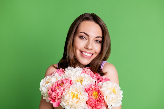 Close-up portrait of her she nice attractive pretty lovely charming cute cheerful cheery glad girl enjoying festal event date occasion holding in hands bunch flowers isolated green color background