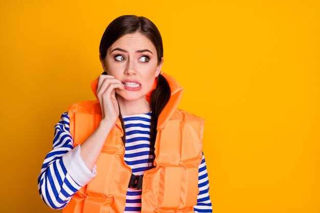 Close-up portrait of her she nice attractive pretty lovely nervous scared brown-haired girl wearing lifesaver biting nails worrying isolated over bright vivid shine vibrant yellow color background