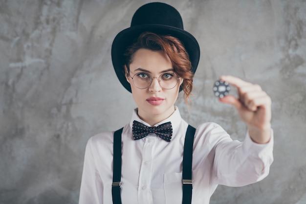 Close-up portrait of her she nice attractive serious content wavy-haired girl wife holding in hand giving you play token try fortune isolated on gray concrete industrial wall background