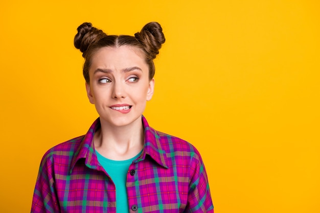 Close-up portrait of her she nice attractive worried girl wearing checked shirt biting lip making solution copy space isolated bright vivid shine vibrant yellow color background