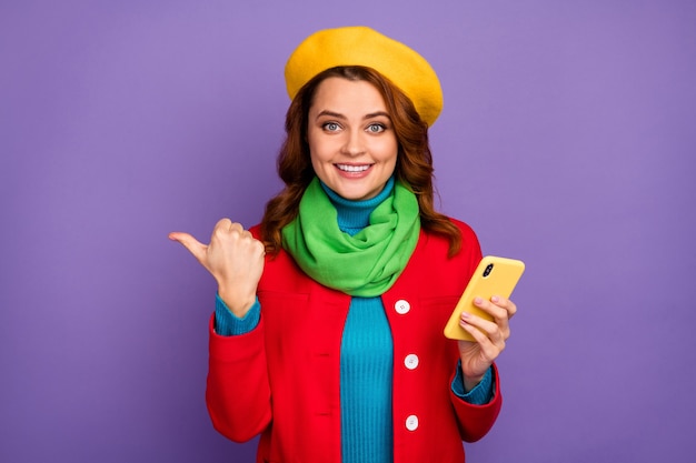 Close-up portrait of her she nice-looking attractive lovely pretty fashionable cheerful wavy-haired girl using cell pointing thumb ad advert isolated over violet lilac purple pastel color background