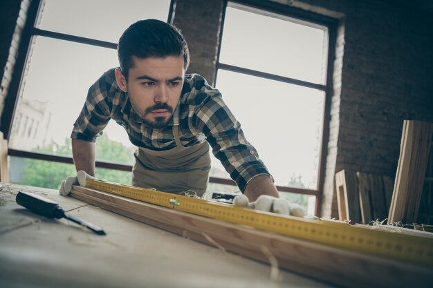 Close-up portrait of his he nice attractive serious concentrated focused skilled hardworking guy checking smoothness plank creating design project at modern industrial loft style interior studio