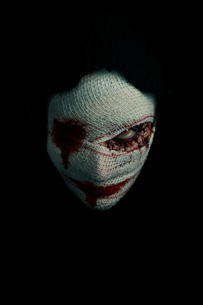 Photo close-up portrait of human face with bandage and paint against black background