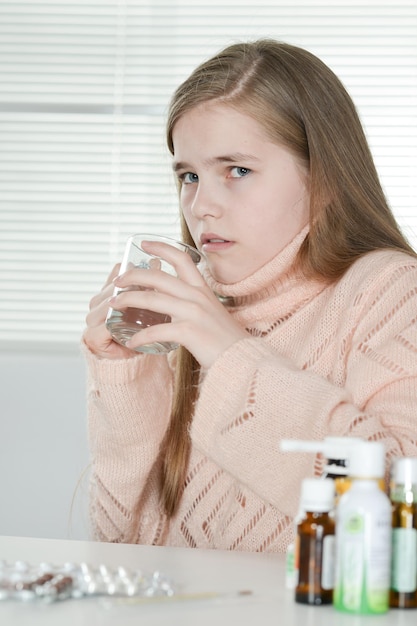 家で薬を飲んでいる病気の女の子の肖像画をクローズアップ