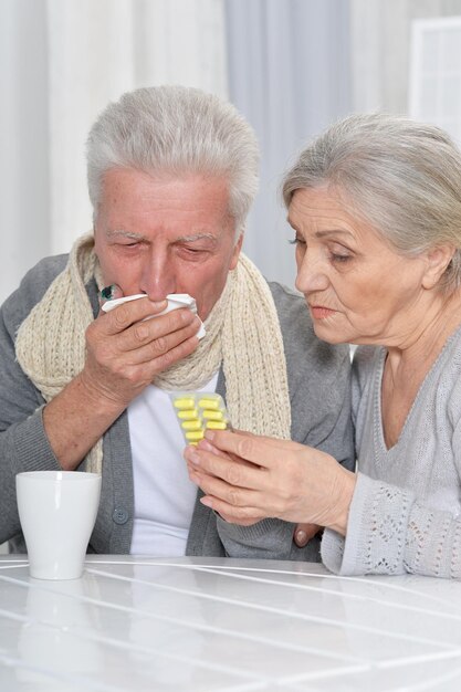 自宅で錠剤と病気のシニアカップルの肖像画をクローズアップ