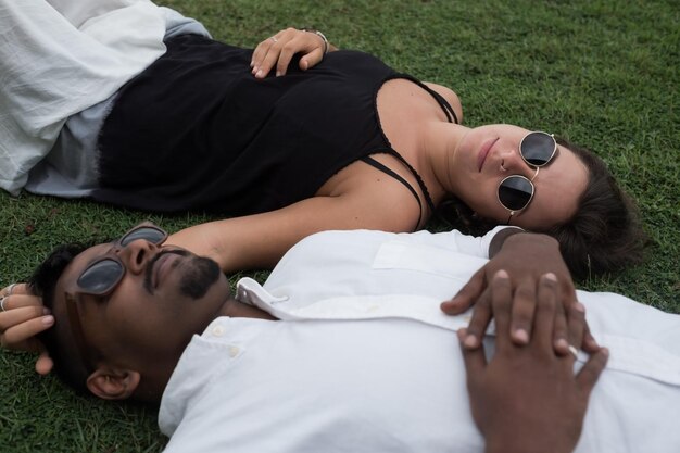 Close up portrait of just married couple lying on grass together in love Concept of international marriage