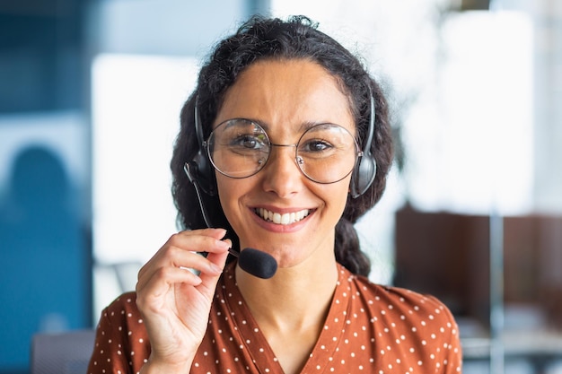 Close up portrait of latin american woman inside modern office\
with headset for video call woman