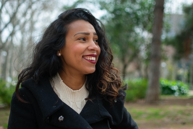 Close up portrait of a latin woman with curly hair posing outside