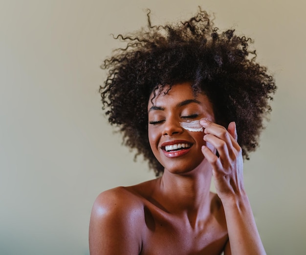 Photo close up portrait of latina woman applying facial cream to her face