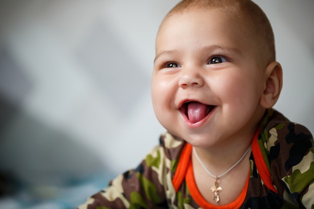 Close-up portrait of a little boy age 8 months and is smiling. Dressed in military costume