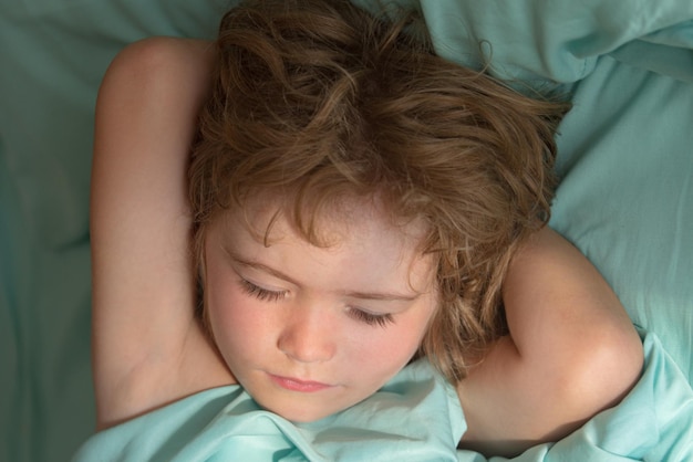 ベッドで寝ている小さな男の子の子供の肖像画をクローズアップ