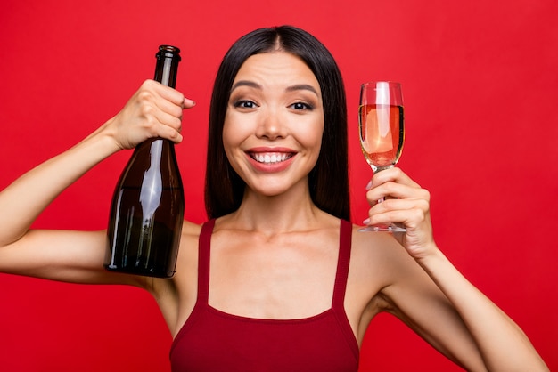 Close up portrait of lovely girl with cocktail in hand isolated on red wall