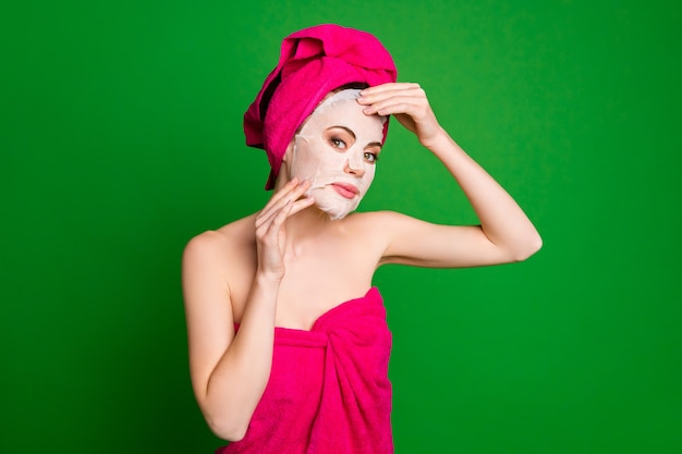 Close-up portrait of lovely lady wearing turban applying facial mask daily therapy isolated over bright green color background